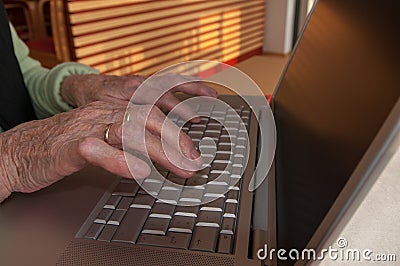 Close up of senior woman`s hands working on computer keyboard Stock Photo