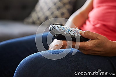 Close Up Of Senior Woman Sitting On Sofa Holding TV Remote Stock Photo