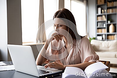 Close up serious focused woman looking at laptop screen Stock Photo