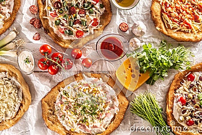 A close up a set of hungarian traditional langos with crusty garlic edges served with vegetables, cream sausages, herbs Stock Photo