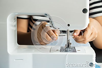 Close up of sewing machine and seamstress` hand Stock Photo