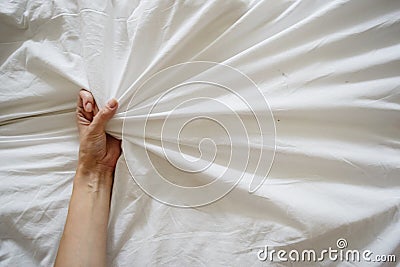 Close up sexy woman hand pulling and squeezing white sheets in ecstasy in bed. Orgasm on white bed. Sex and erotic Stock Photo