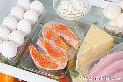 Close-up shelf in the fridge where red fish, eggs, cheese, cottage cheese, mushrooms and meat Stock Photo