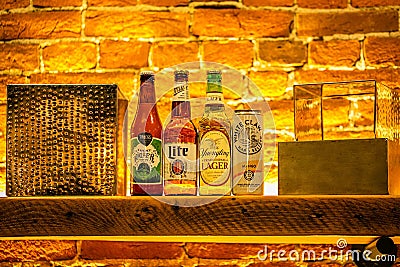 Close-up of a shelf of various types of alcoholic beverage bottles illuminated with light in a bar Editorial Stock Photo