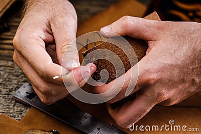 Close up of a shoemaker or artisan worker hands. Leather craft tools on old wood table. Leather craft workshop. Stock Photo
