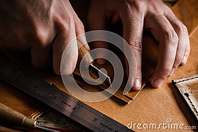 Close up of a shoemaker or artisan worker hands. Leather craft tools on old wood table. Leather craft workshop. Stock Photo