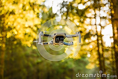 Close up shoot of a DJI Quadcopter Drone Mavic mini 249g. Drone flying in sunny forest. DJI is the market leader in drones and Editorial Stock Photo