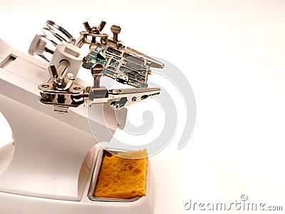 Close up shoot of printed circuit board PCB sitting on a white repair stand with magnifier for better examining small parts Stock Photo