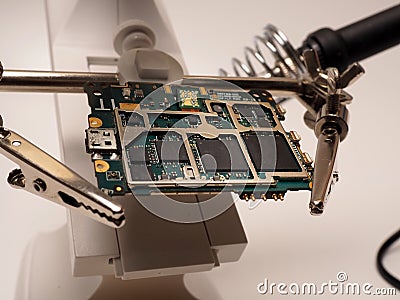 Close up shoot of printed circuit board PCB sitting on a white repair stand with magnifier for better examining small parts Stock Photo