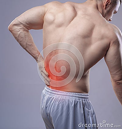 Close up shot. Athletic muscular man has pain in the back. Red spot of backache Stock Photo