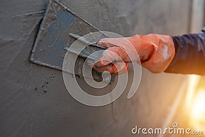 Close-up shot of a cement worker using a trowel to plaster the walls Stock Photo