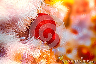 Close-up shot of Christmastide decoration with red balls and white fir tree on golden lighting bokeh background. Stock Photo