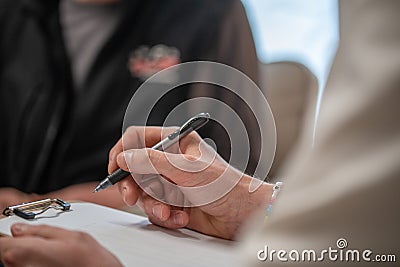 Close-up shot of a female professional writing something on a clipboard during a therapy session Stock Photo