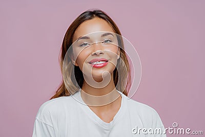 Close up shot of feminine girl smiles gently at camera, wears minimal makeup, has healthy skin, fair hair, feels pleased to get Stock Photo