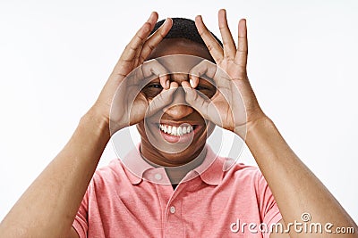 Close-up shot of funny and playful good-looking kind and happy african american guy showing okay gesture as binoculars Stock Photo