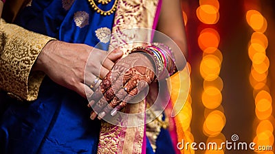 close up shot of groom and bride& x27;s hands in which they are wearing engagement rings with bookeh background of lighting Stock Photo