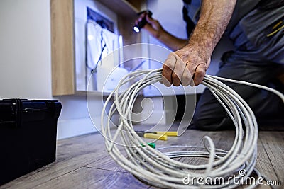 Close up shot of hand of aged electrician, repairman in uniform working, fixing, installing an ethernet cable in fuse Stock Photo