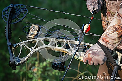 Close up shot of a hunter dressed in camouflage clothing holding a modern bow. Stock Photo