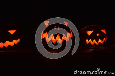 Close-up shot of illuminated carved pumpkins in a dark room Stock Photo