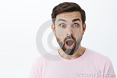 Close-up shot of impressed and shocked stunned caucasian guy with beard dropping jaw from amazement popping eyes at Stock Photo