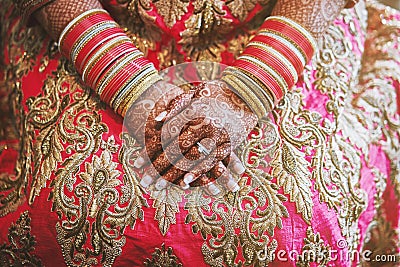 The hands of Indian bride with menhdi henna tattoo and bunch of glitter bangles on her wrist, close-up Stock Photo