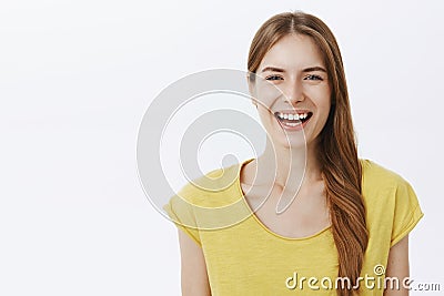 Close-up shot of kind happy charming european woman with braid in yellow birght t-shirt smiling joyfully at camera Stock Photo