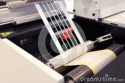 Close-up shot of labels manufacturing on flexo printing machine. Photo detail of matrix waste or trim removal from adhesive. Stock Photo