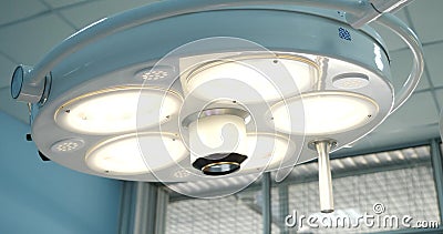 A close-up shot of a luminous surgical lamp in the operating room. A round lamp hangs over the table and shines brightly Stock Photo