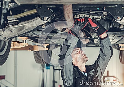 Mechanic Fixing Car Hoisted Up On Hydraulic Lift Stock Photo