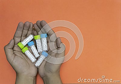 Close-up shot of a man hands holding bottle of homeopathic pills on apricot background. Medicine and treatment concept Stock Photo