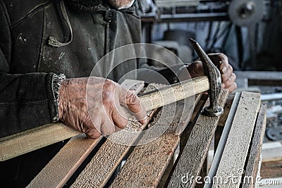 Close up shot of master carpenter working in his woodwork or workshop. Hammer in old hand Stock Photo