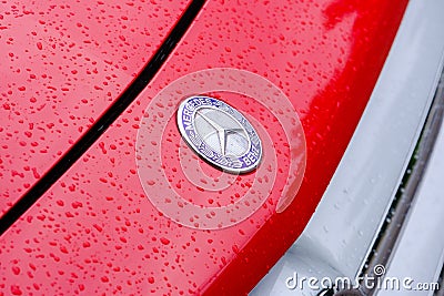 Close-up shot of Mercedes Benz badge on a red GLA with water droplets on it Editorial Stock Photo