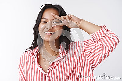Close-up shot of optimistic and energized outgoing friendly woman in striped blouse showing victory or peace gesture Stock Photo