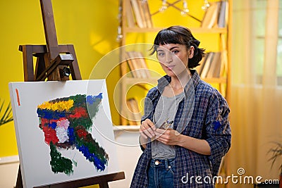A close up shot of the painter woman dabbing into her collide palette with her brush and painting something onto the Stock Photo