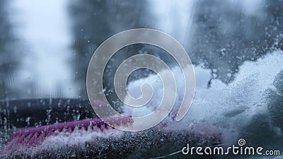 Close up shot of a person removing the snow from a car frozen windshield with ice scraper. Stock Photo