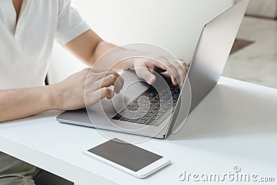 A close-up shot of person typing on computer laptop with the phone stand by ii Stock Photo