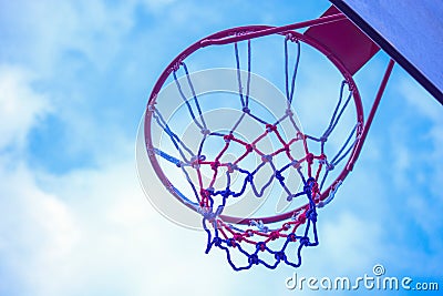 Close-up shot of a pink basketball hoop with a background of a cloudy sky Stock Photo