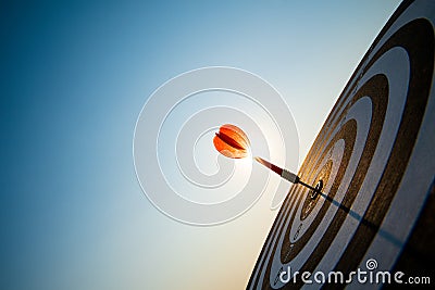 Close up shot red darts arrows in the target center on dark blue sky background. Business target or goal success and winner Stock Photo
