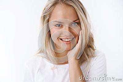 Close-up shot of satisfied pleased sensual blond woman touching soft and silk skin on cheek smiling delighted and Stock Photo