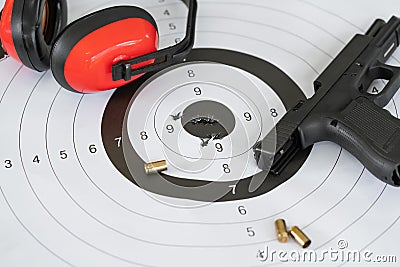 Close up shot of a shooting target and bullseye with bullet holes with automatic pistol gun and cartridge bullet. Stock Photo