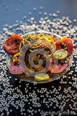 Close up shot of spicy tasty sabudana khichdi or sago ball khichdi along with some sliced tomatoes, some cut lemons in a glass Stock Photo