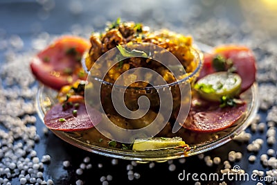 Close up shot of spicy tasty sabudana khichdi or sago ball khichdi along with some sliced tomatoes, some cut lemons in a glass pla Stock Photo