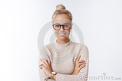 Close-up shot of successful good-looking blond european woman in glasses with bun haircut cross arms over chest smiling Stock Photo