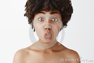 Close-up shot of tender and gentle silly naked woman with afro hairstyle folding lips and awaiting for passionate kiss Stock Photo