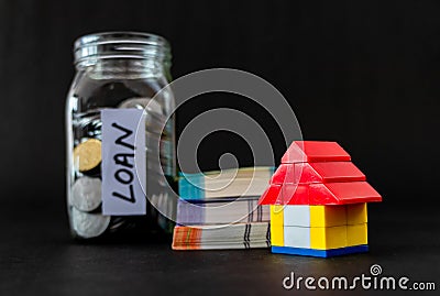 Close up shot of a toy house with money notes and coin filled glass jar defocused in background Stock Photo