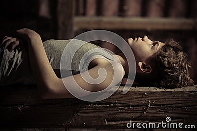 Close up side view of boy laying on wooden bench Stock Photo