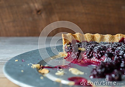 Close up side view of a dark berry tart made with blackberries and blueberries on a galvanized tray. Copy space. Stock Photo