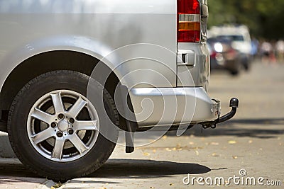 Close-up side view detail of silver passenger medium size luxury minibus van with tow-bar parked on summer sunny city street Stock Photo