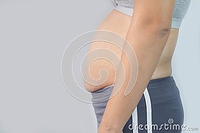 Close-up side view of woman excessive belly fat on gray background. Woman fat belly. Obesity and Overweight Concept Stock Photo