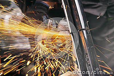 Close-up on the sides fly bright sparks from the angle grinder machine. Stock Photo